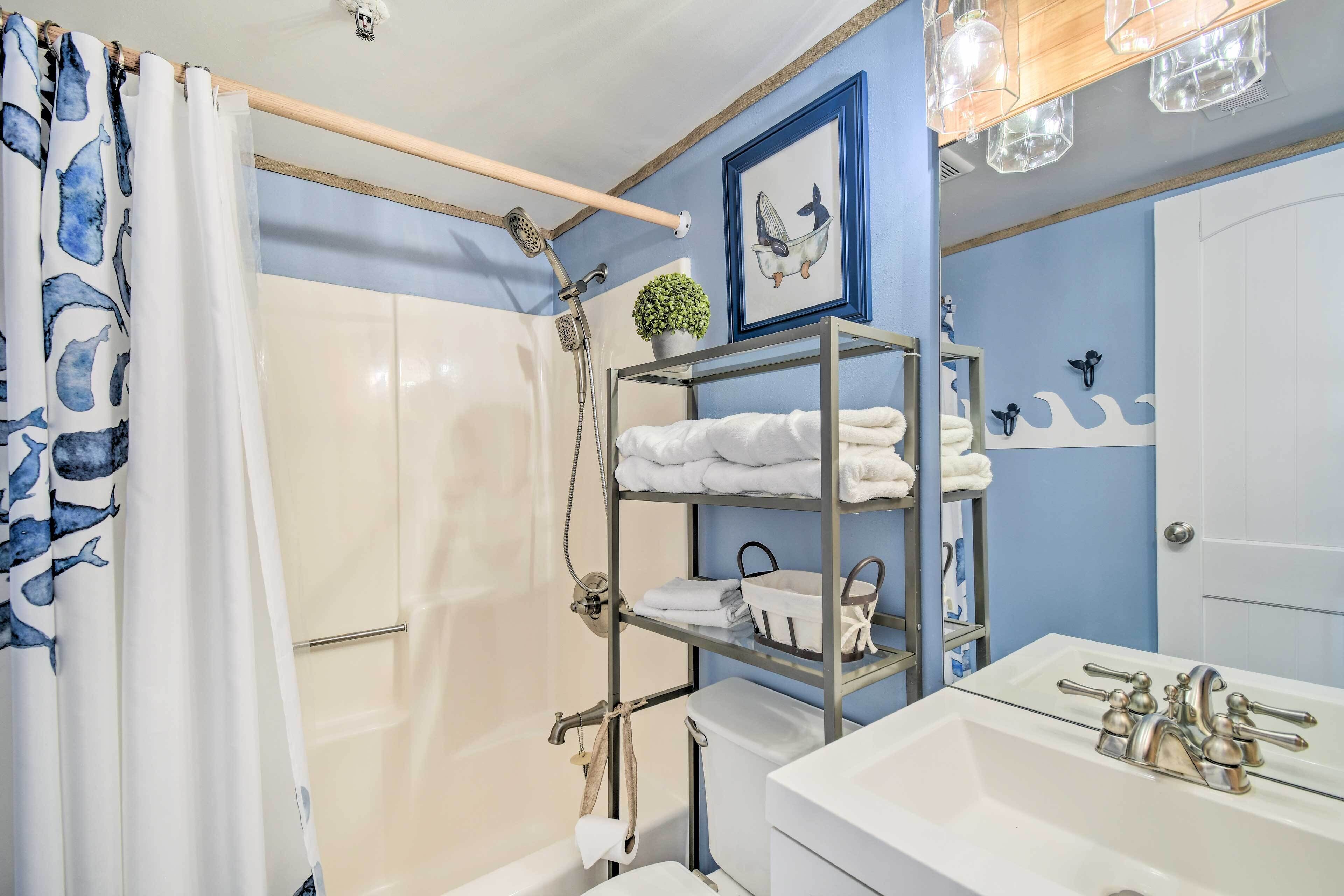Une salle de bain avec une douche, un lavabo, un porte-serviettes et un tableau encadré au mur.
