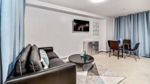 Ein modernes Wohnzimmer mit einem Ledersofa, einem runden Couchtisch und einem Essbereich mit Tisch und Stühlen.