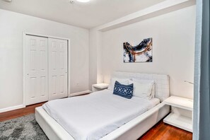 A modern bedroom with a large bed, white walls, and a door. - New and Cozy 1BD Apt in the Heart of Philly! (Philadelphia)