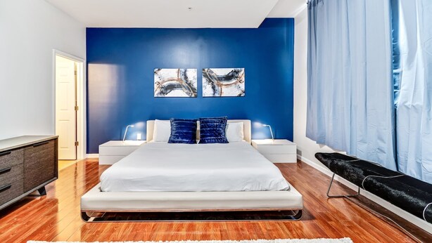 Quarto moderno com uma cama grande, duas mesas de cabeceira, um penteado e uma janela com cortinas.