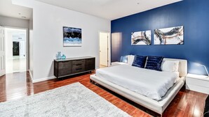 Um quarto com uma cama grande, uma cômoda branca e uma parede azul decorativa.