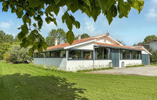 A modern house with a tiled roof, large windows, and a well-maintained lawn.