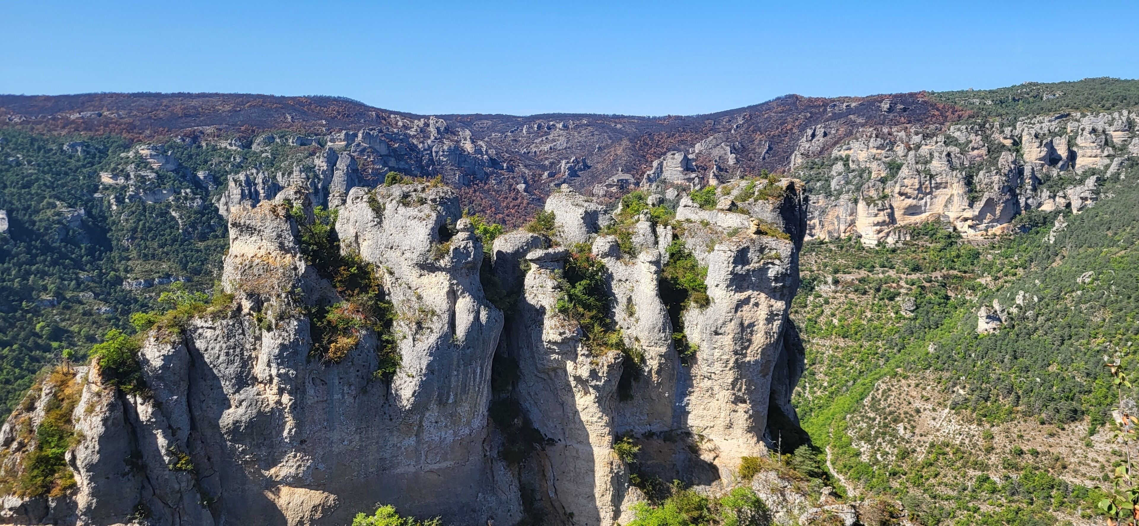 Paisagem montanhosa com formações rochosas imponentes e vegetação escassa.