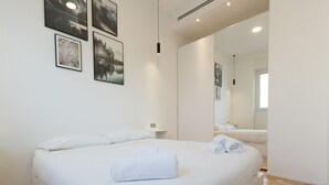 Ein modernes Schlafzimmer mit einem großen Bett, einem Nachttisch und einem Spiegel.