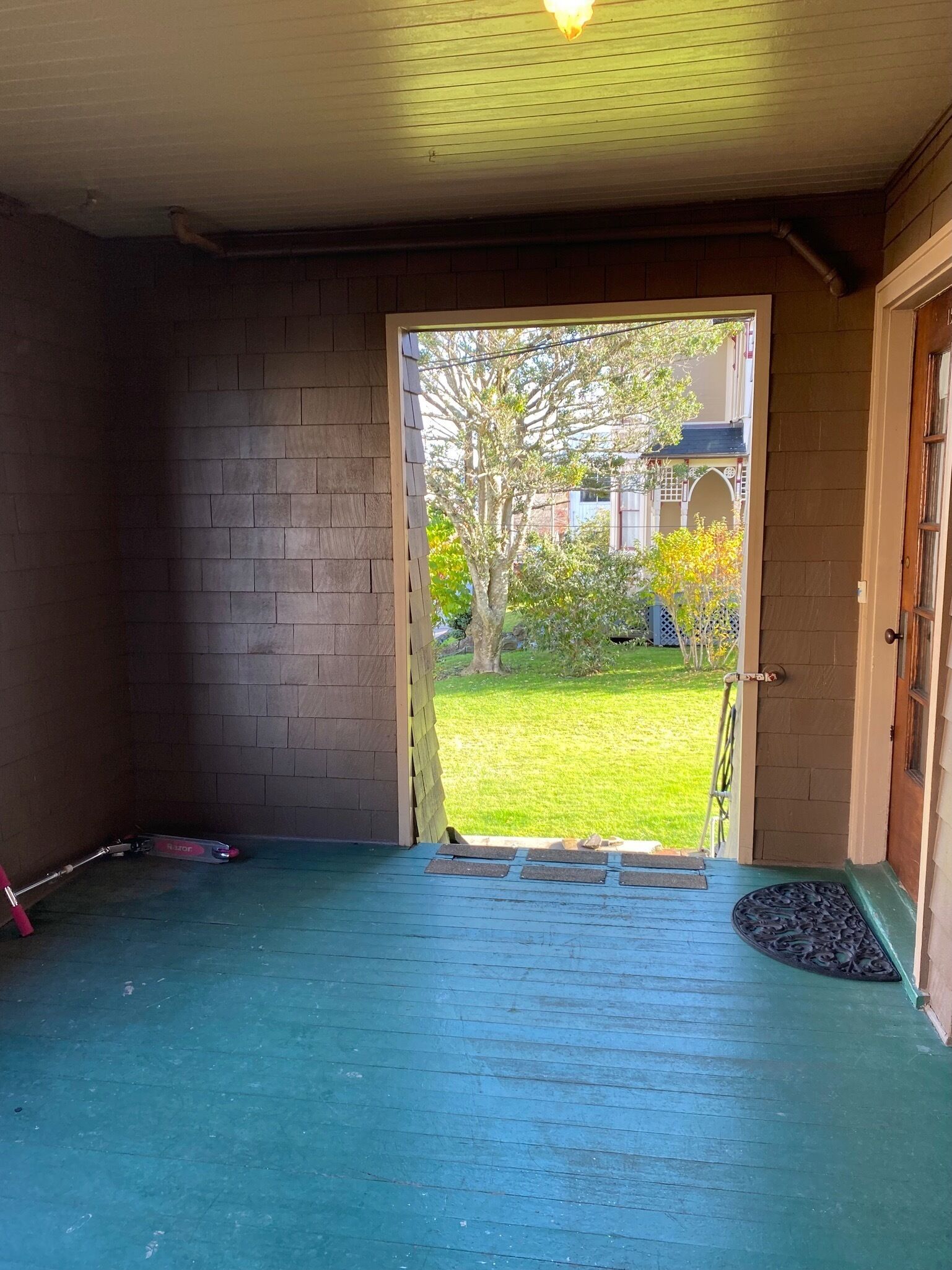 A room with a wooden door leading to a covered outdoor area.