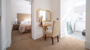 Ein Hotelzimmer mit Bett, Schminktisch mit Spiegel, Stuhl und Blick ins Freie.