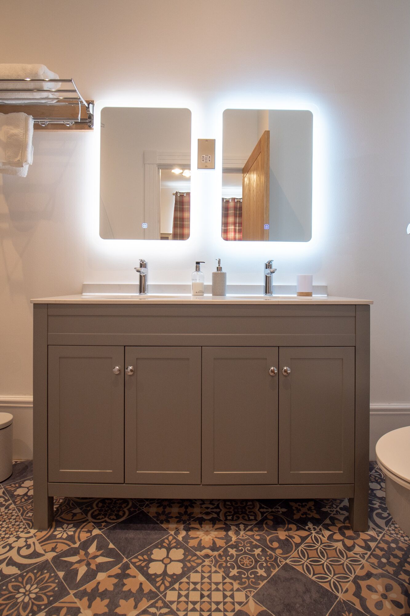 A bathroom with a double vanity, two mirrors, and a tiled floor.