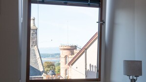 Ein Fenster mit Blick auf ein historisches Gebäude und einen klaren Himmel.