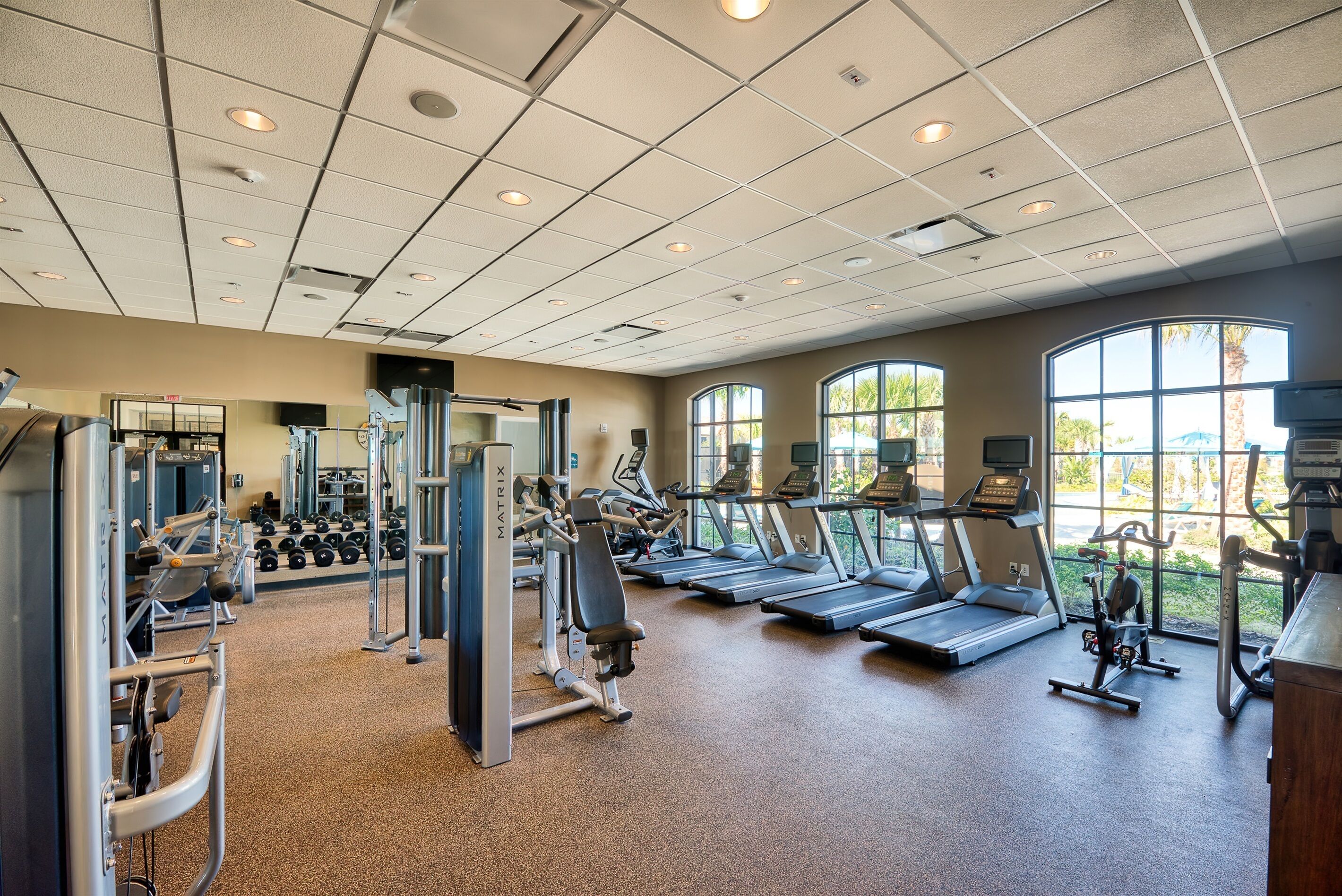 Une salle de sport équipée de tapis de course, d’appareils de musculation et de poids libres.