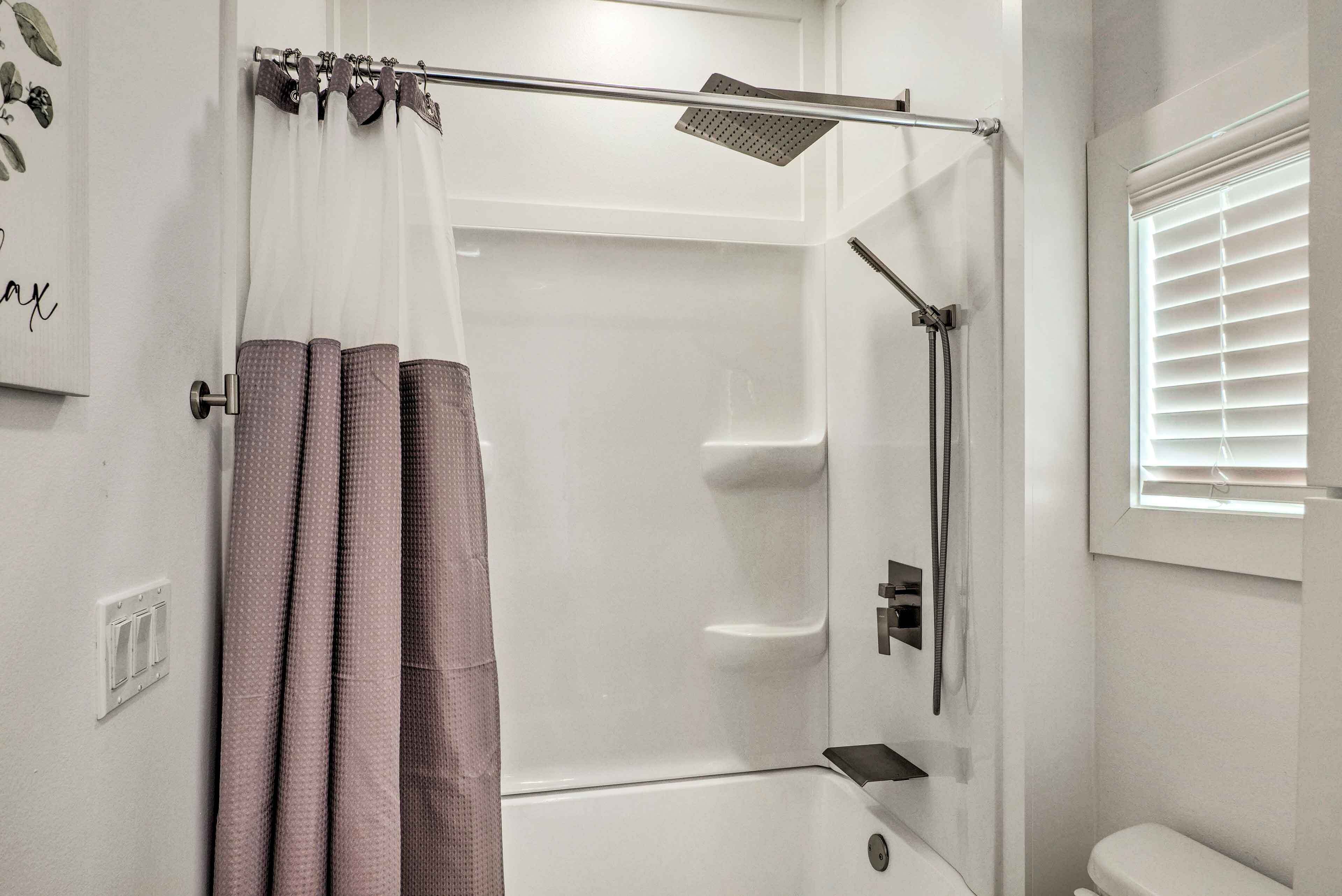 Un baño moderno con ducha, inodoro y ventana con persianas.