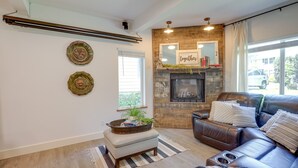 A living room with a fireplace, leather sofa, and decorative plates on the wall. - Farmhouse w/ Private Hot Tub < 1 Mile to Birch Bay (Blaine)