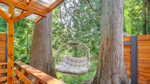 A wooden deck with a hanging chair and a bench, surrounded by large trees. - Farmhouse w/ Private Hot Tub < 1 Mile to Birch Bay (Blaine)