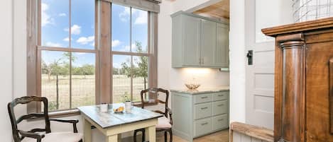 A kitchen with a dining table, two chairs, and a view of the outdoors.