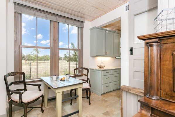 Una cocina con una mesa de comedor, dos sillas y vistas al exterior.