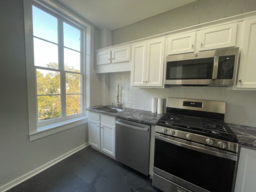 A kitchen with white cabinets, a stainless steel stove, a microwave, and a dishwasher.