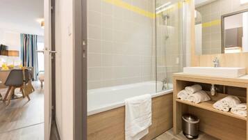 Une salle de bain moderne équipée d’une baignoire, d’une douche et d’un meuble-lavabo avec des serviettes.
