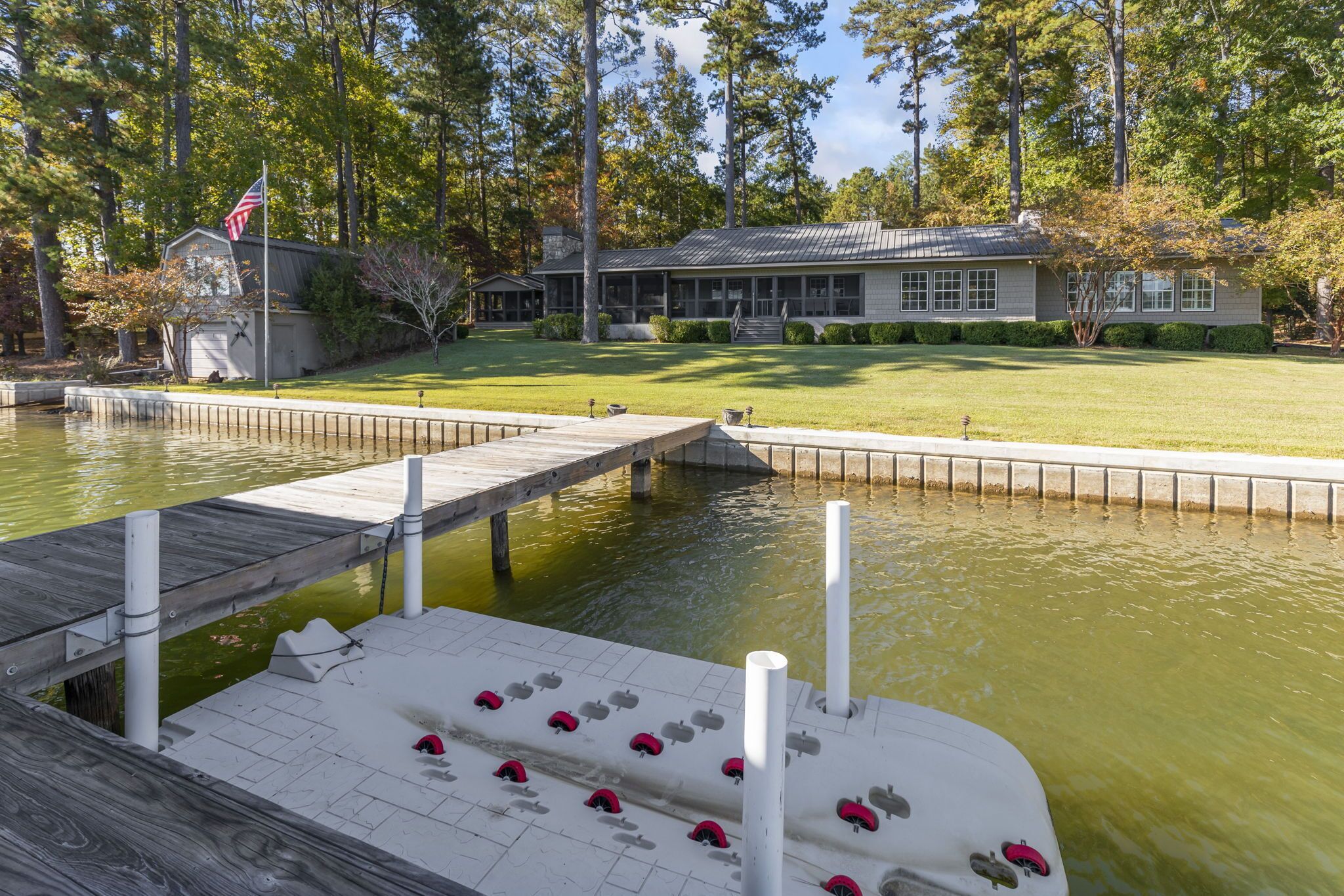 A dock extending into a pond with a house in the background.