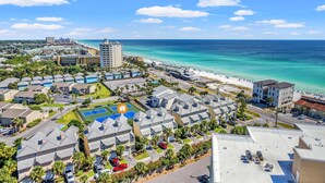 A coastal resort with multiple buildings, a beach, and a clear blue sky.