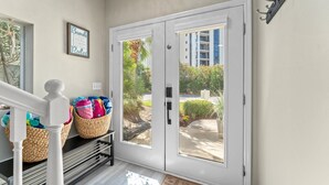 A clean, modern entrance with a white door, wicker baskets on a shelf, and a framed sign on the wall.