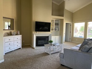 A living room with a fireplace, a television, a sofa, and a coffee table. - 3BR Family Home with Pool & Hot Tub (Fresno)
