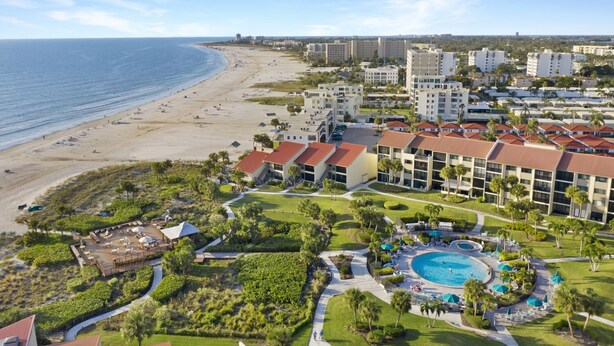 Un resort con vista a la playa, varias edificaciones y una zona de piscina.