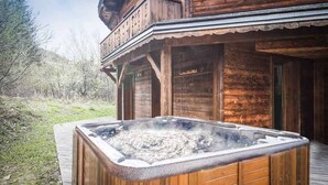 A wooden cabin with a hot tub in front.