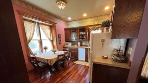 Une cuisine avec des meubles en bois, un réfrigérateur et un coin repas comprenant une table et des chaises.