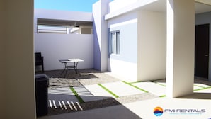 A modern, open-plan living space with a minimalist design, featuring a dining area, a seating area, and a large window providing natural light.