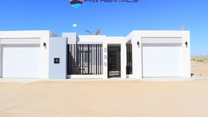A modern building with a gated entrance, two garage doors, and a clear blue sky.
