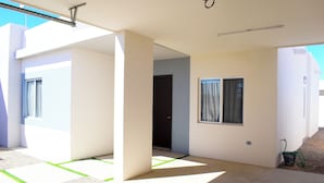 A modern house with a covered patio, a door, and a window with curtains.