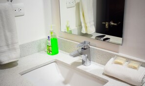A bathroom with a white sink, a mirror, and a towel rack.
