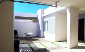Un espace de vie moderne et ouvert, conçu dans un style minimaliste, comprenant un coin repas, un coin salon et une grande fenêtre laissant entrer la lumière naturelle.