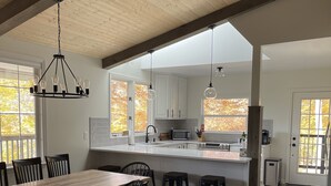 A spacious kitchen with white cabinets, a large island, and pendant lighting. - Secluded cabin in Hocking County (New Straitsville)