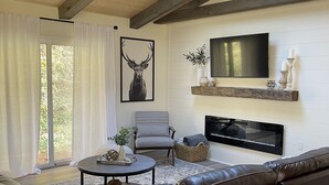 A living room with a leather sofa, a round coffee table, a fireplace, and a TV mounted on the wall. - Secluded cabin in Hocking County (New Straitsville)