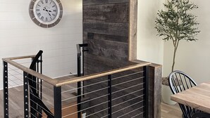 A modern interior with a wooden staircase, a dining area, and a wall-mounted clock. - Secluded cabin in Hocking County (New Straitsville)
