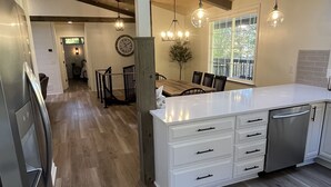 A modern kitchen with a central island, wooden flooring, and pendant lighting. - Secluded cabin in Hocking County (New Straitsville)