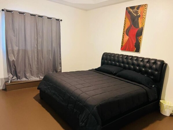 A bedroom with a large bed, a grey curtain, and a painting on the wall. - Grand estate in upscale neighborhood w/ nice pool (Mission)