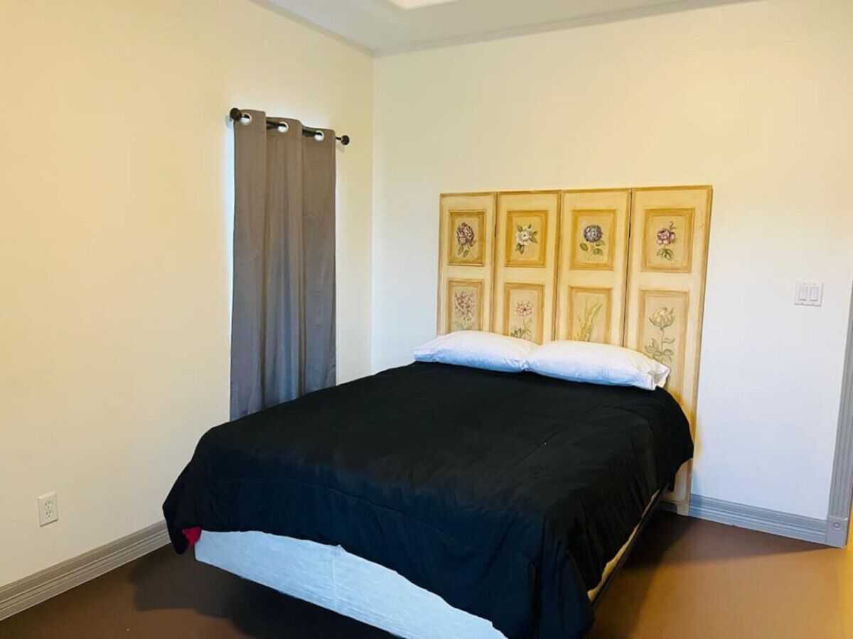 A bedroom with a bed, a curtain, and a wall with floral decorations.
