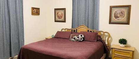 Un dormitorio con una cama grande, dos mesitas de noche y cortinas.