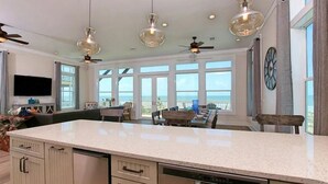 A spacious kitchen with a large island, pendant lighting, and a view of the ocean. - Luxurious 6-Bedroom Oceanfront Home with Private Pool in Gulf County. (Port St. Joe)