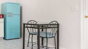 Eine kleine Küche mit einem blauen Kühlschrank, einem Tisch mit zwei Stühlen und einem weißen Schrank.