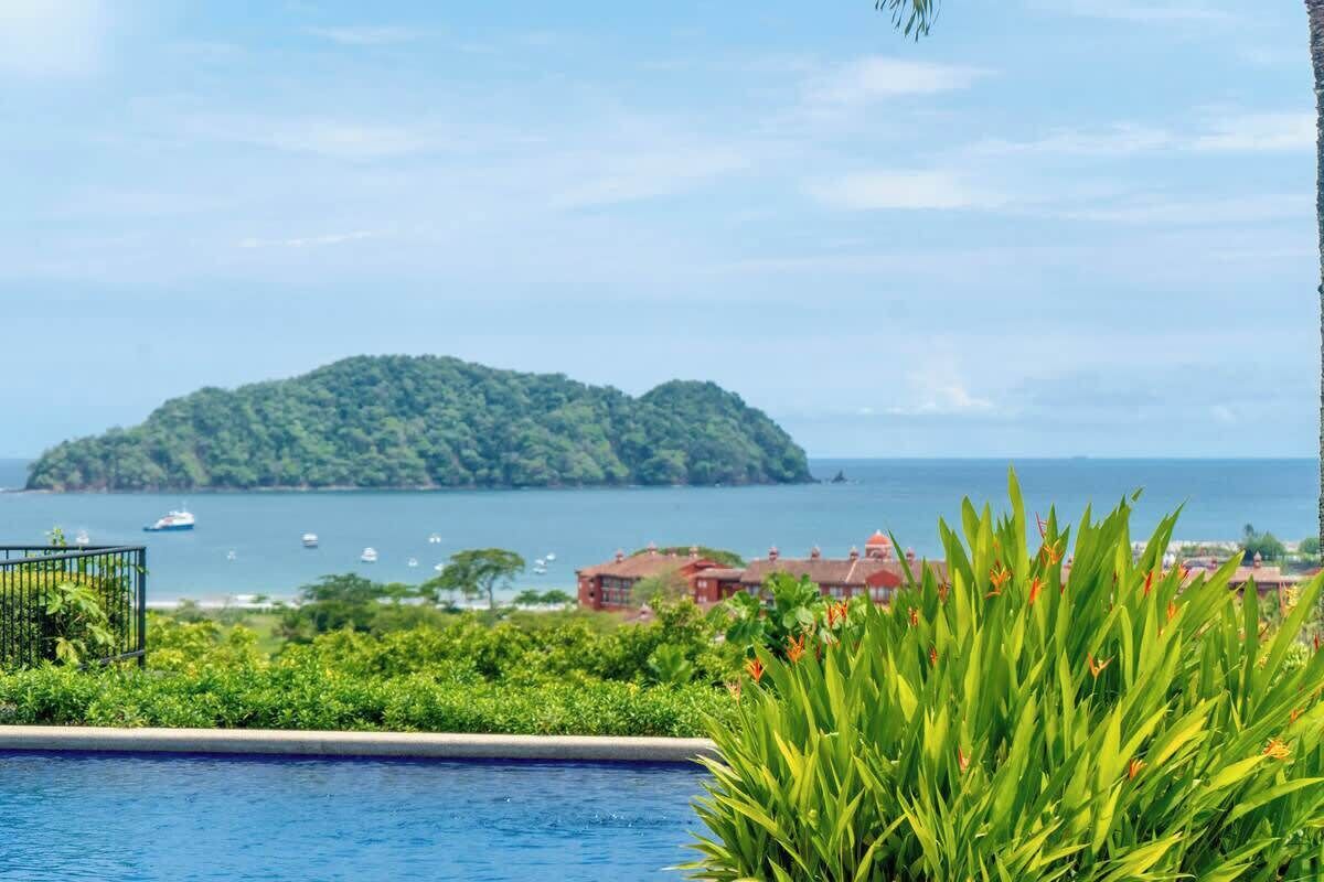 A swimming pool with a view of a lush green island and the sea.