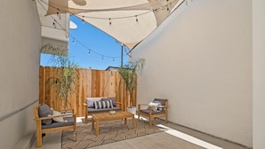 A patio with a wooden fence, a sofa, a chair, a coffee table, and string lights. - Mid Century Artsy Home in the Heart of NORTH PARK (San Diego)