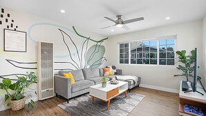 A modern living room with a grey sofa, a white coffee table, and a ceiling fan. - Mid Century Artsy Home in the Heart of NORTH PARK (San Diego)