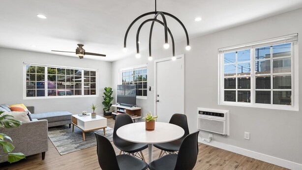 A modern living room with a round table, black chairs, a grey sofa, a ceiling fan, and a TV. - Mid Century Artsy Home in the Heart of NORTH PARK (San Diego)