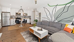 A modern kitchen with white cabinets, a stainless steel refrigerator, and a dining area with a table and chairs. - Mid Century Artsy Home in the Heart of NORTH PARK (San Diego)