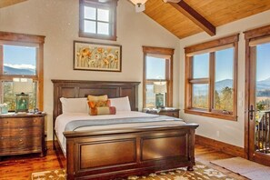 Un dormitorio con una cama grande, cabecera de madera y varias ventanas con vistas panorámicas.