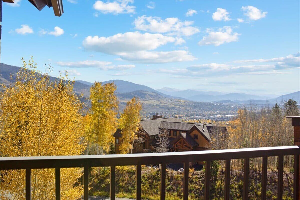 A mountain cabin with a view of autumn foliage and distant mountains.