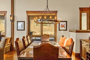 Un comedor con una mesa larga, sillas de cuero, un candelabro y cuadros en las paredes.