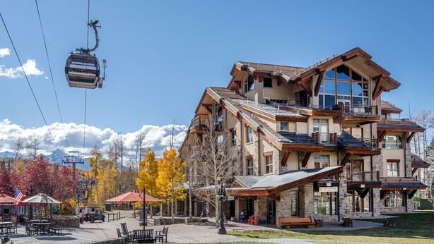 A multi-story building with a ski lift cable, outdoor seating, and a mountain backdrop. - Gorgeous Granita Ski in/Ski out (Telluride)